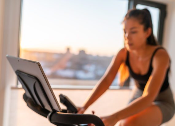 Women uses her smart gym bike in her home.