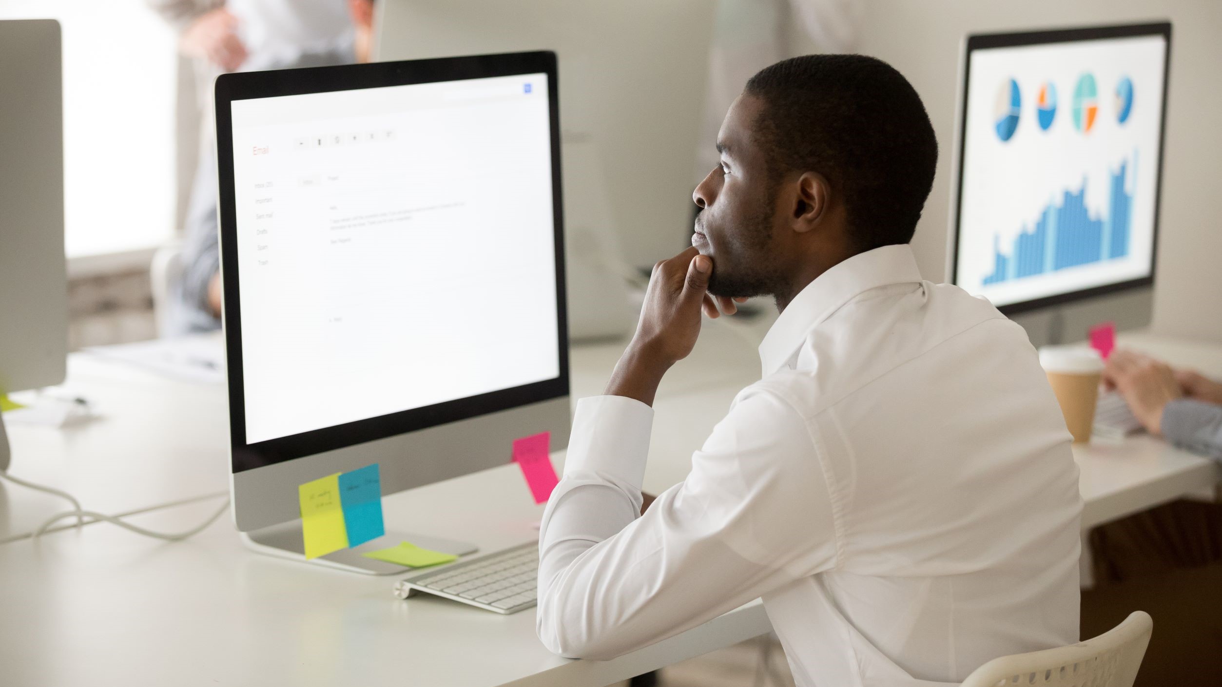 Young man checks his email at his work computer.