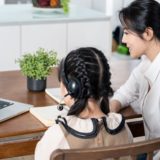Mother helps her elementary-school age daughter with her online learning classes.