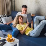 A couple watches a YouTube video together on a table in their living room.