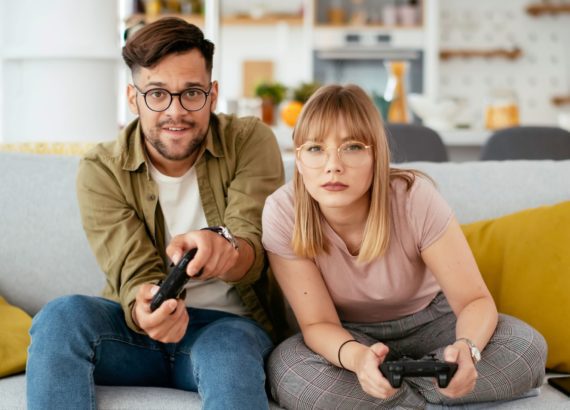 A couple plays a racing video game on their couch.
