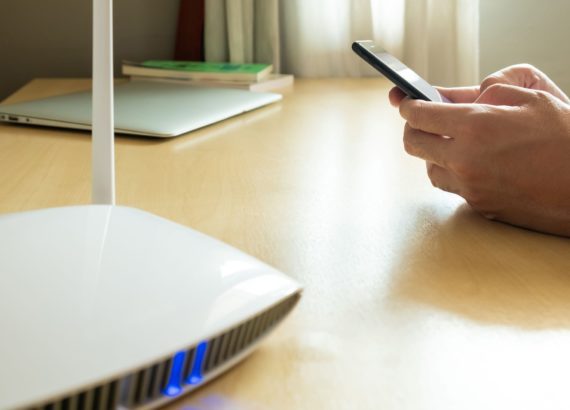 A man uses his smartphone to change his router administrative settings to secure his WiFi. 