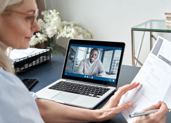 An HR professional reviews a resume as she interviews a candidate over video chat.