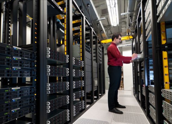 An IT worker types on a computer in a data center.