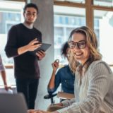 Small business owner works on a computer during a meeting with her staff.