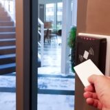 A resident uses a key card to enter an apartment building.