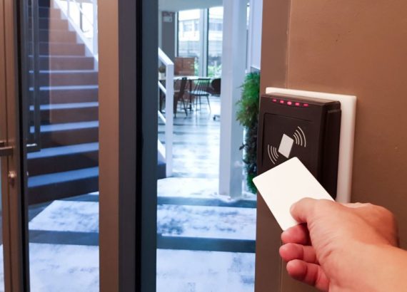 A resident uses a key card to enter an apartment building.