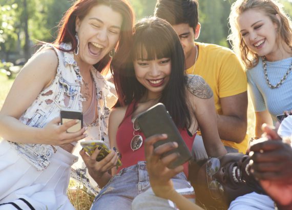 A group of friends gathered with their cell phones practices social media privacy.