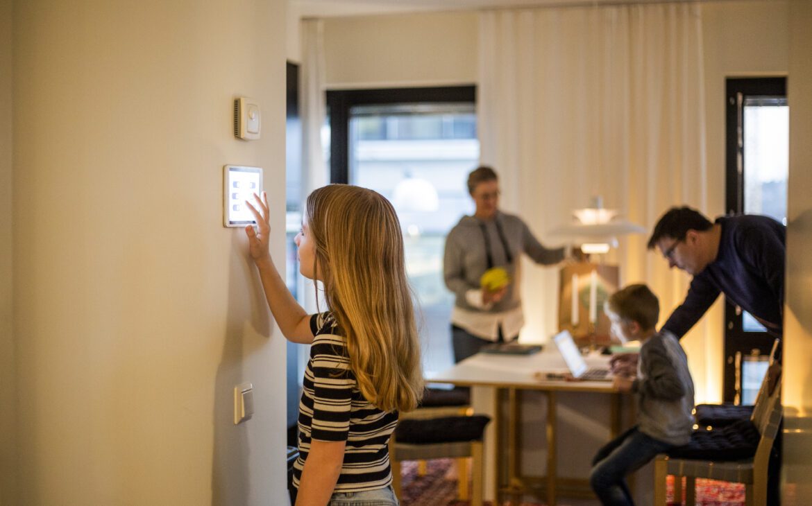 A young girl uses a smart home thermostat, keeping internet of things security in mind.