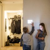 Two kids use a smart home thermostat, practicing good internet of things security.