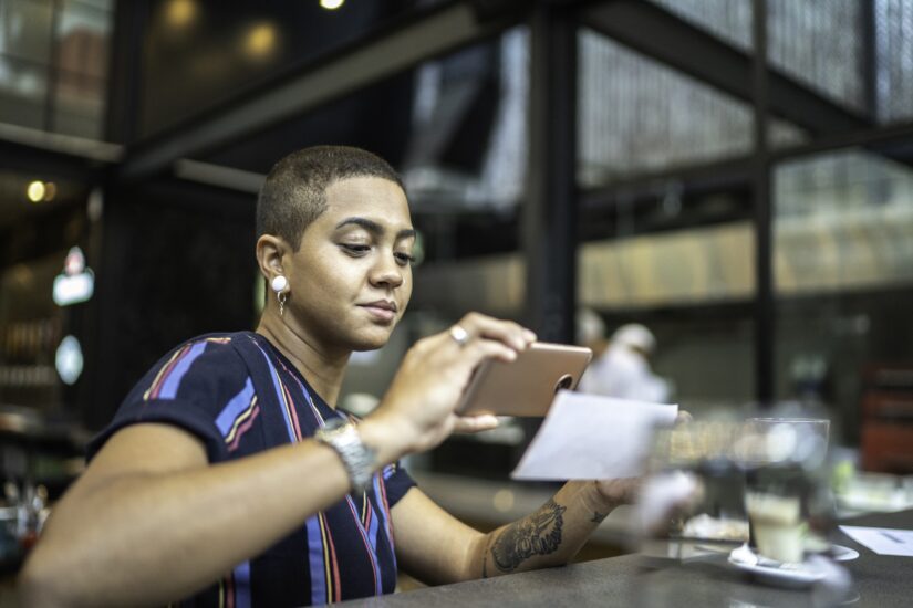 A woman deposits a check at a cafe with an online banking app.