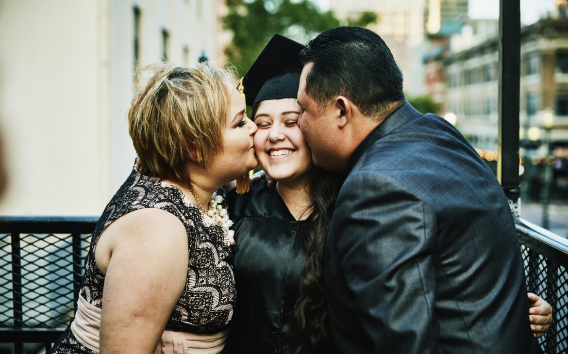 Mom and dad kissing their new grad