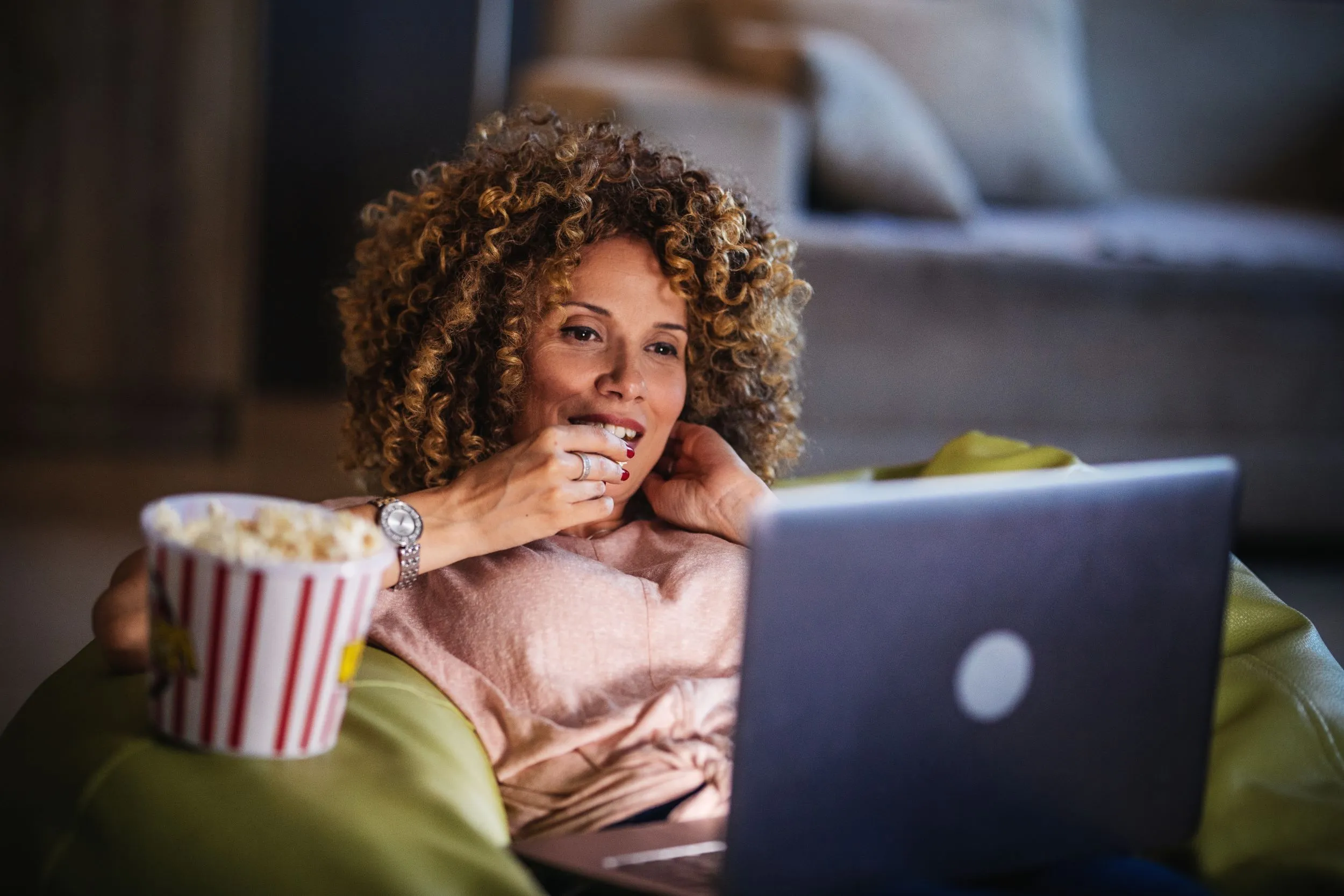 Women at home streaming on laptop eating popcorn