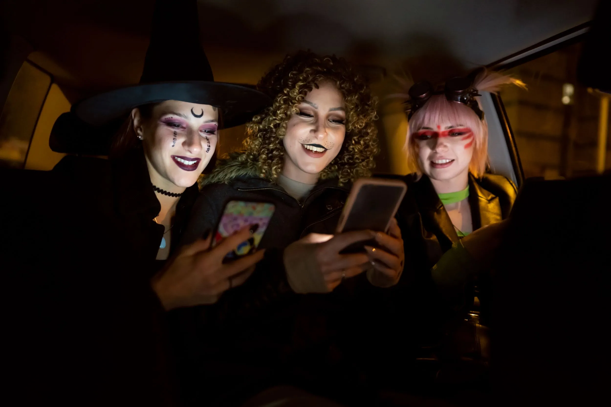 3 witches using mobile devices in taxi