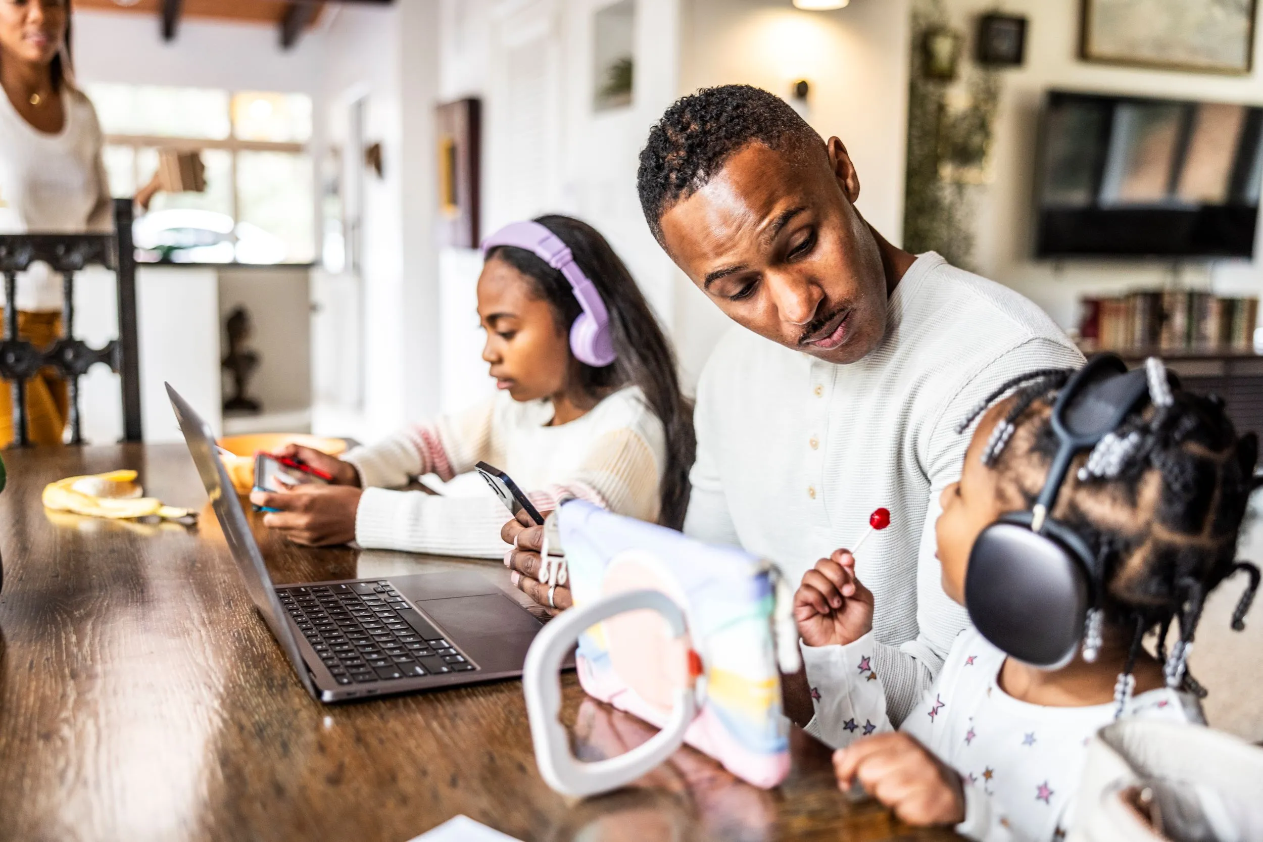 Father working while daughters next to him play video games