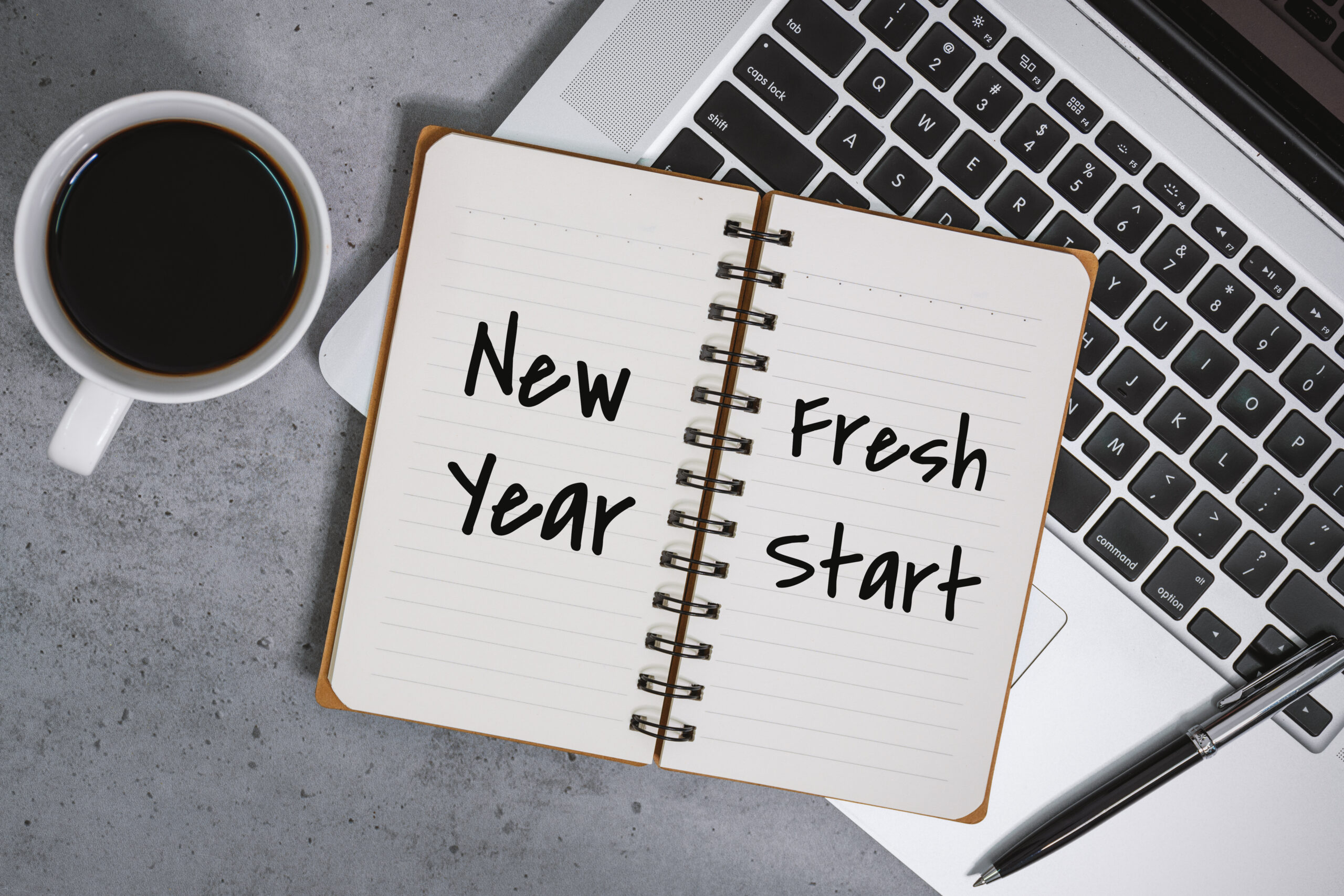 New Year Fresh Start on Notebook With Laptop Over Work Desk