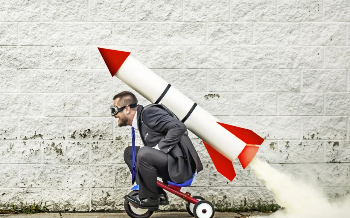 Guy on tricycle strapped to a rocket on his back