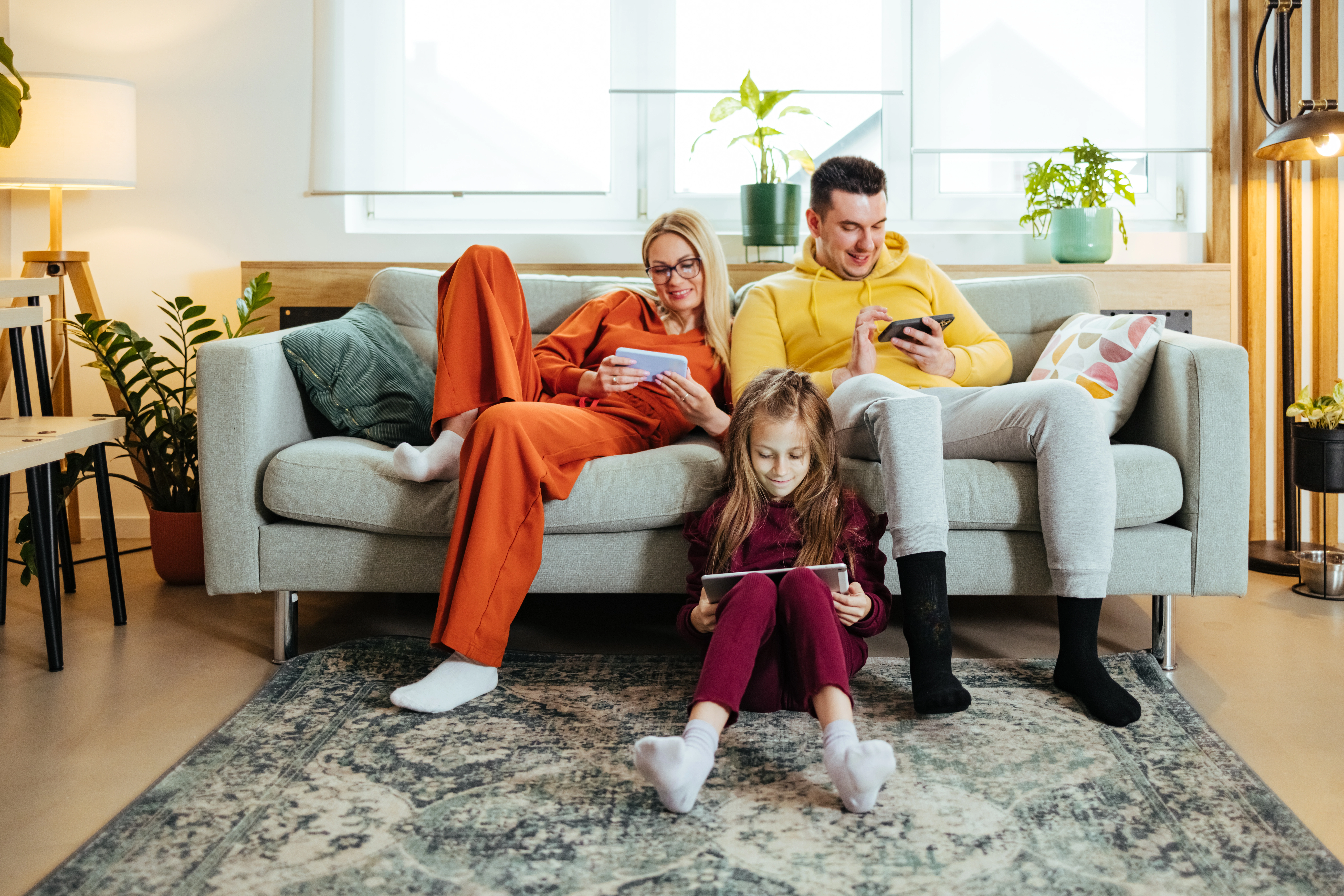 Family with devices sitting together on couch