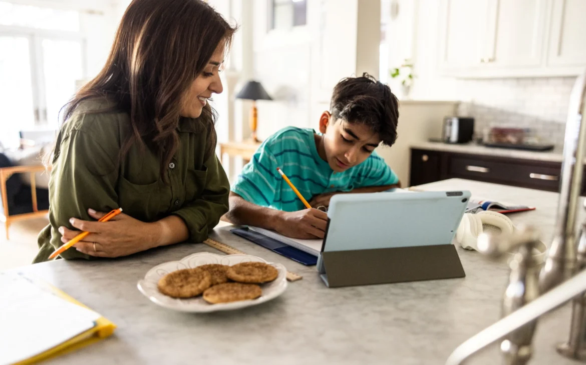 Mom and son doing school work on computer at kitchen table