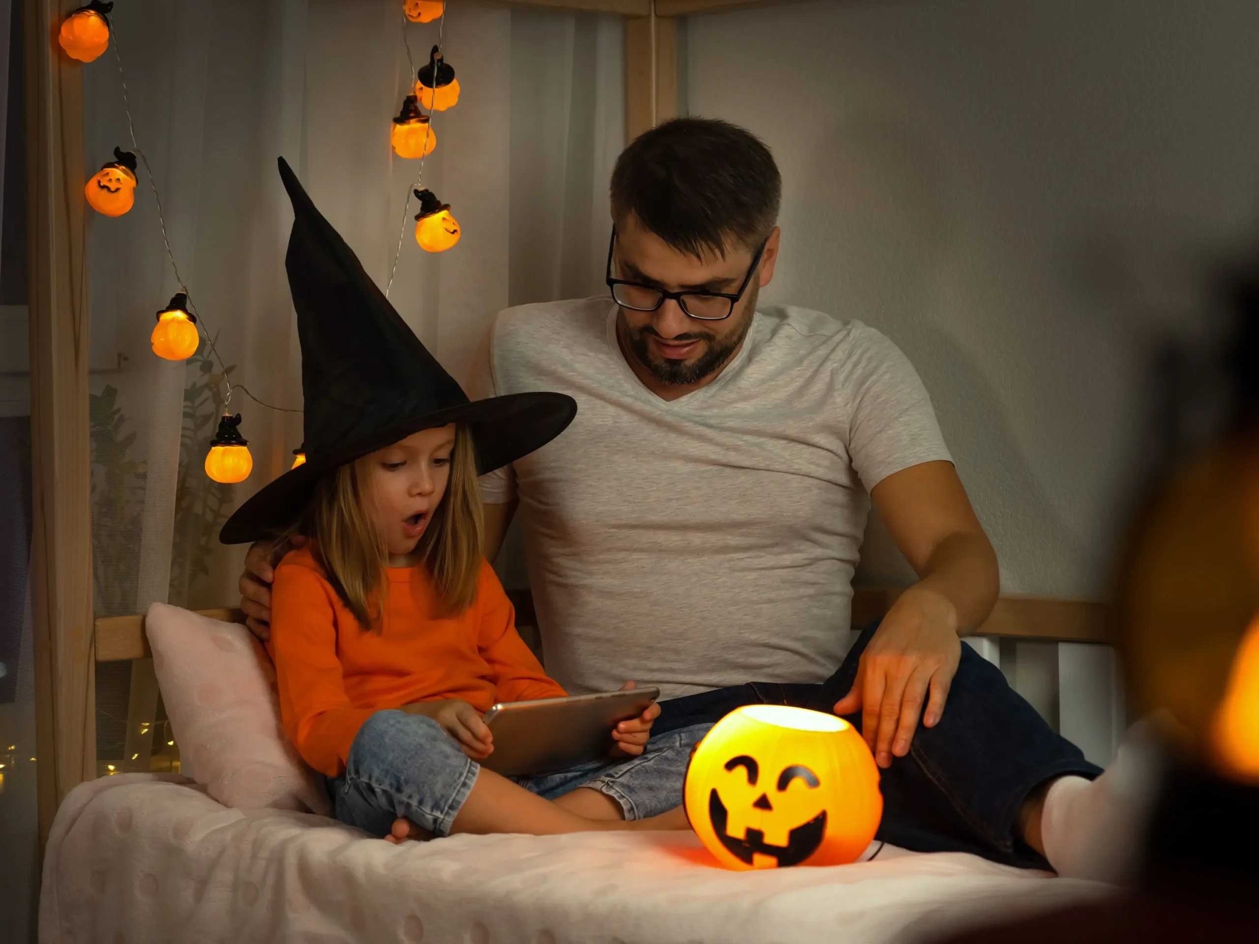 Father and daughter streaming a Halloween moving on tablet